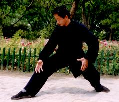 Chinese man doing the taming a tiger pose with hands lowered and legs wide apart